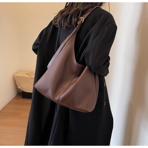 Detail of dark brown lychee leather texture and golden buckle on large hobo bag