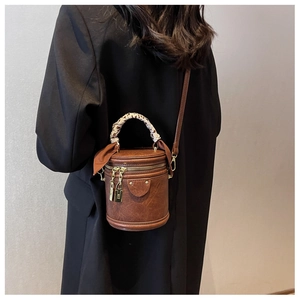 Détail du sac seau cylindrique marron rétro avec poignée en foulard et ferrures dorées