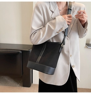 Detail of black patchwork bucket bag in matte suede and smooth leather on model