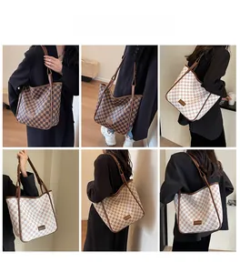 Detail view of large checkered tote bags in brown and beige with long leather straps