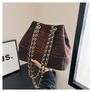 Détail d'un sac seau vintage à carreaux avec chaîne dorée et tissu en tweed texturé