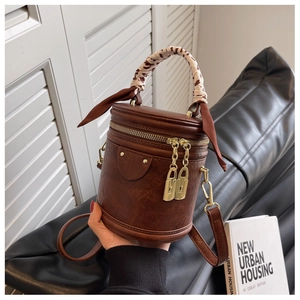 Détail du sac seau marron avec foulard léopard sur la poignée et charms cadenas dorés