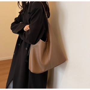 Detail of tan pebble leather hobo bag with large capacity shown on black wool coat