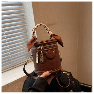 Détail du sac seau marron vintage avec foulard en soie léopard enroulé sur la poignée