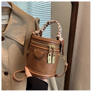 Détail d'un sac cylindrique marron vintage avec foulard léopard et verrous dorés