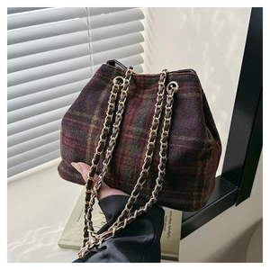 Gros plan d'un sac seau vintage en laine à carreaux avec bandoulière chaîne dorée