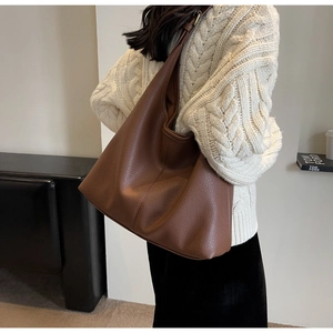 Detailed view of deep brown hobo bag with pebble leather texture on a female model