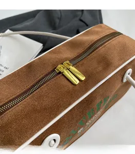 Détail des fermetures éclair dorées sur le sac polochon vintage en daim marron