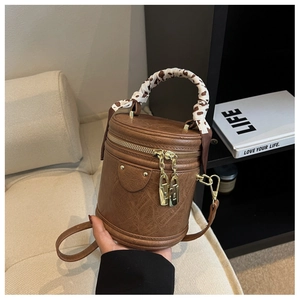 Détail du sac seau cylindrique marron avec poignée en foulard et pendentif cadenas doré
