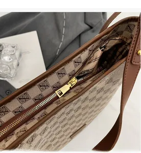 Detail view of smooth golden zipper and geometric jacquard texture on brown tote bag