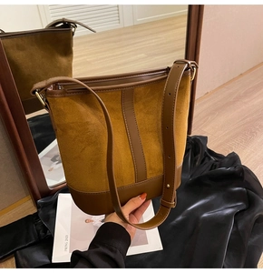 Detail of caramel brown suede bucket bag with adjustable leather strap and metal buckle