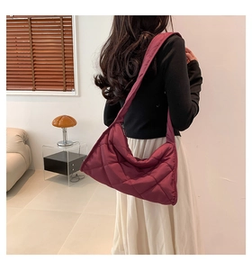 Sac cabas matelassé en nylon bordeaux porté par un mannequin dans un intérieur moderne