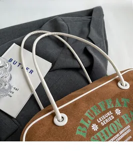 Détail du sac cabas en daim marron avec anses en corde blanche et imprimé vintage