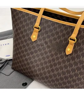 Detail of monogram print tote bag with brown leather straps and gold metal rings