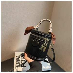 Détail du sac seau noir en cuir avec anse en foulard léopard et fermoirs dorés