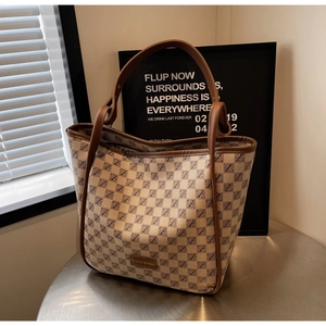 Detail of checkered tote bag with leather handles and spacious interior on a table