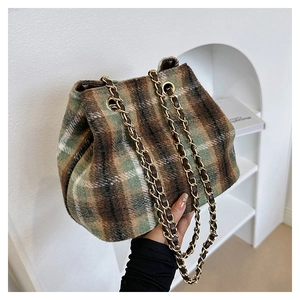Gros plan du sac seau en laine écossaise avec bandoulière chaîne dorée et textile doux