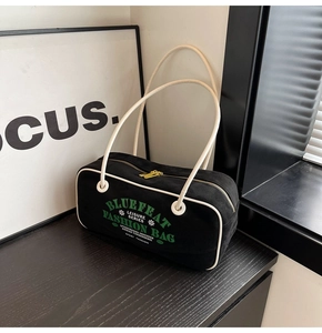 Détail d'un sac bandoulière rétro en toile noire avec texte vert et zip doré