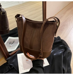 Detail of vintage matte brown bucket bag with mixed textures and adjustable strap