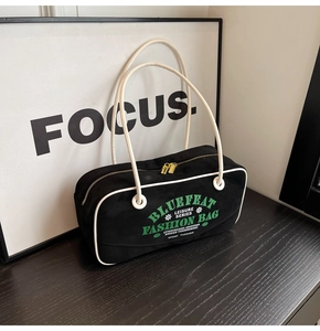 Détail du sac bowling en toile noire avec passepoil contrasté et zips dorés doubles