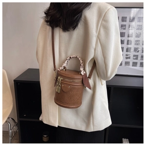 Détail du sac cylindrique marron avec poignée foulard léopard et cadenas dorés