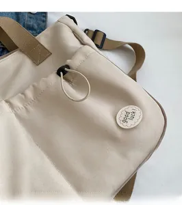 Detailansicht der beigen Canvas-Tasche mit Kordelzugtasche und Good Luck Stickerei