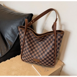 Detail of checkered tote bag with fashion tag on a stone surface in warm coffee tones