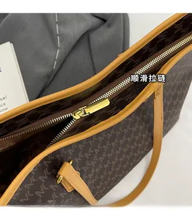 Detailed close-up of the golden metal zipper and retro monogram pattern on a tote bag