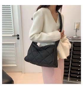 Détail du sac polochon en nylon noir matelassé avec un motif de losanges élégants