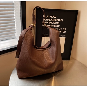 Detail of large brown lychee leather hobo bag with gold metal buckle and wide shoulder strap