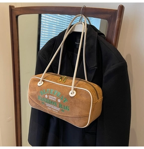 Vue détaillée du sac à bandoulière en cuir mat marron avec texte brodé et zip doré