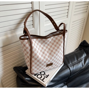 Detailed macro view of cream tote bag with brown checkered pattern and metal logo plate