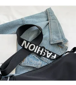 Detail of adjustable wide black crossbody strap with bold white FASHION lettering