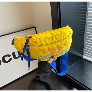 Detail van gele nylon crossbodytas met blauwe banden en gepixelde gedrukte belettering