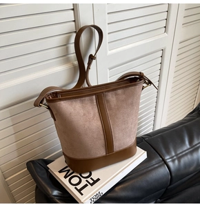 Detailed close-up of brown suede and leather bucket bag with premium gold metal zipper