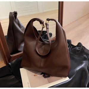 Detailed close-up of dark brown pebbled leather texture and adjustable metal buckle on tote