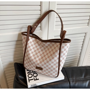 Detail of checkered tote bag with leather trim on white book and leather sofa