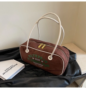 Gros plan d'un sac baril en daim marron avec liseré blanc et logo sur cuir noir