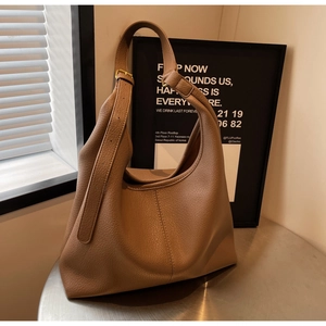 Detailed close-up of caramel pebbled leather hobo bag on a table with soft natural lighting