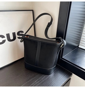 Macro detail of black matte fabric and glossy leather trim on a large bucket shoulder bag