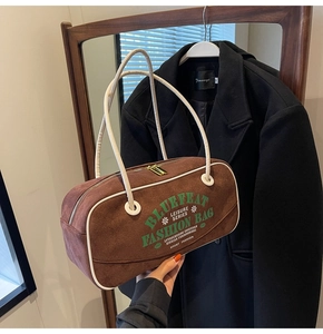 Détail du sac Boston en daim marron avec surpiqûres blanches et zip doré élégant