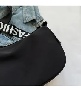 Detail of black nylon shoulder bag with FASHION logo strap on blue denim jacket