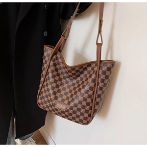 Detail of checkered tote bag showing leather strap and fashion & bags metal plaque