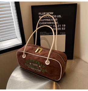 Détail du sac cylindrique en daim marron rétro avec passepoil blanc et fermetures éclair dorées