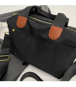 Detail of black nylon tote with brown lychee leather trim and gold metal rivets