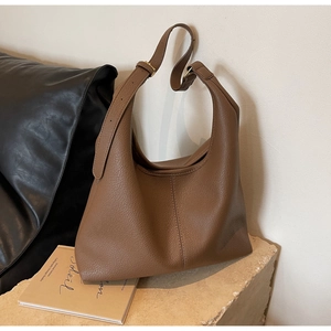 Close-up of caramel brown leather hobo bag showing pebbled texture and adjustable strap