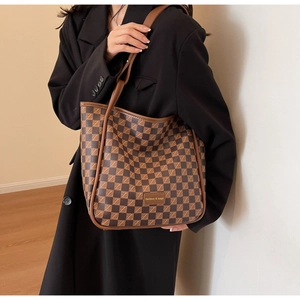 Detail of checkered tote bag showing metal brand tag and high-quality PU leather texture