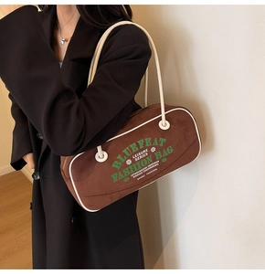 Détail du sac à bandoulière en daim marron vintage avec lettrage rétro et passepoil blanc