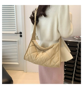 Détail du sac à bandoulière matelassé beige montrant la texture douce et le volume
