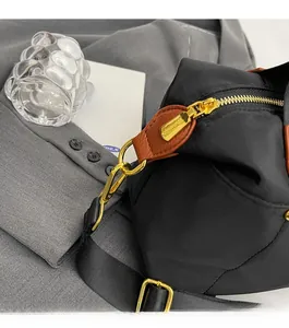 Detail of black nylon pillow bag with gold metal zipper and brown leather puller